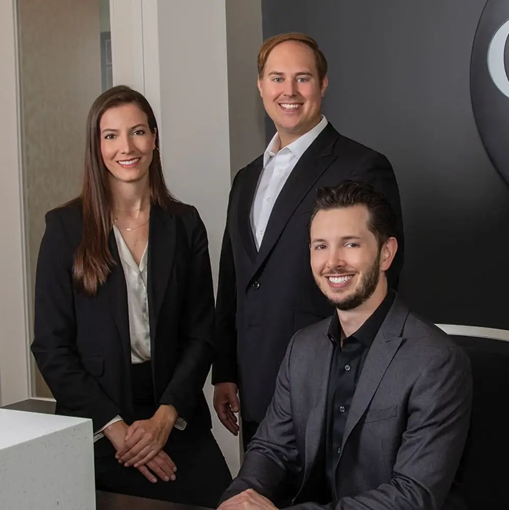 Dr. Andrea Emmerich, Dr. Jake Jacomet, and Dr. Nicholas Dwan sitting at the front desk of Glo Dental Studio in Waukesha, WI.